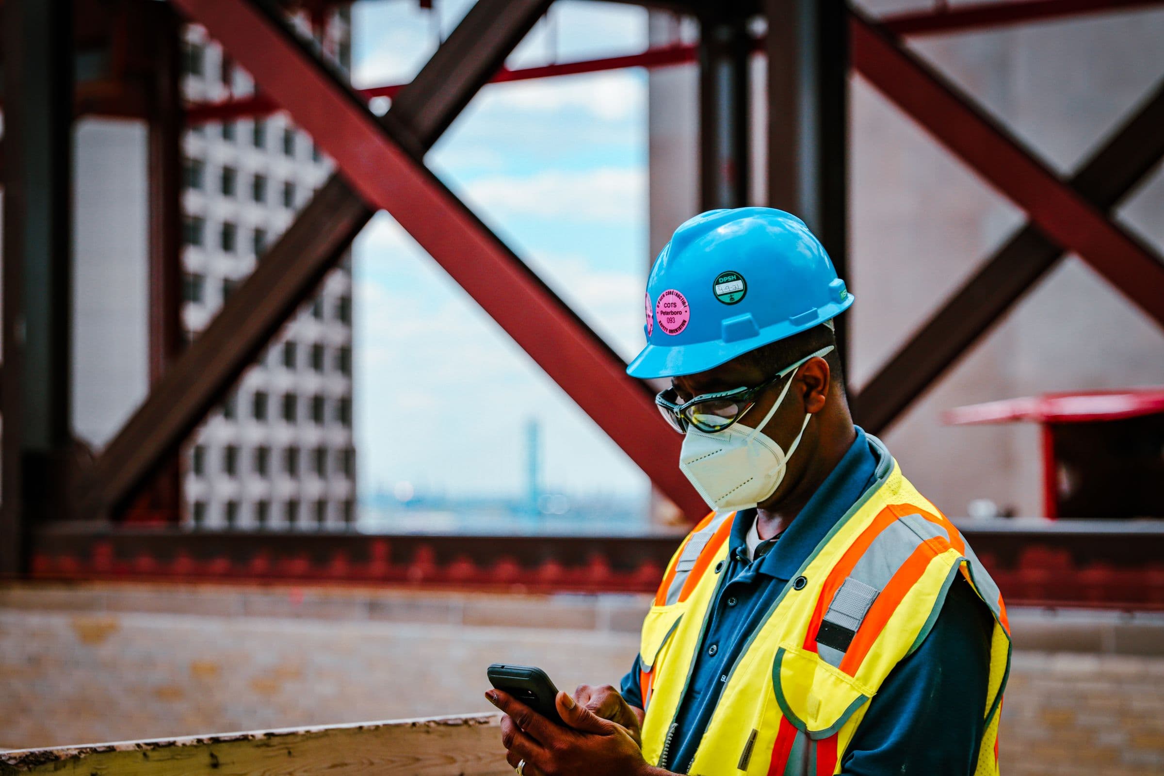 Trades worker in a hard hat and high-visibility vest on the phone.
